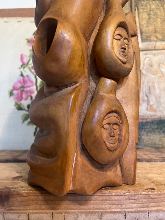 Vintage handmade abstract wood sculpture in mid century modern style with faces depicted.