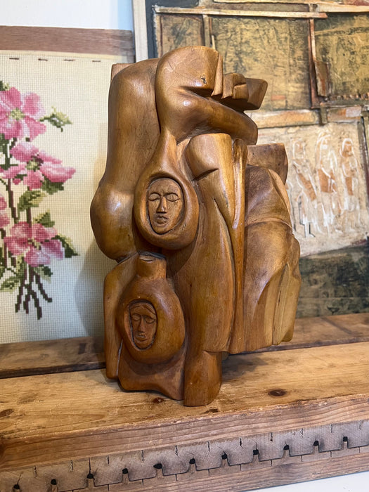 Vintage handmade abstract wood sculpture in mid century modern style with faces depicted.