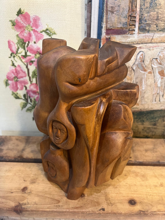 Vintage handmade abstract wood sculpture in mid century modern style with faces depicted.