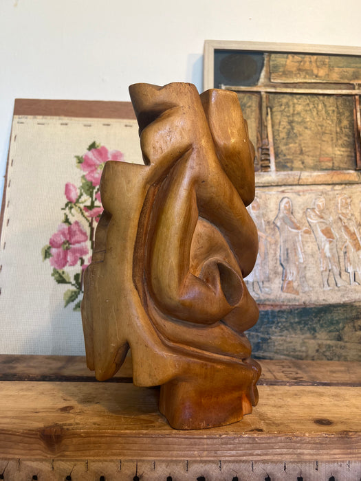 Vintage handmade abstract wood sculpture in mid century modern style with faces depicted.