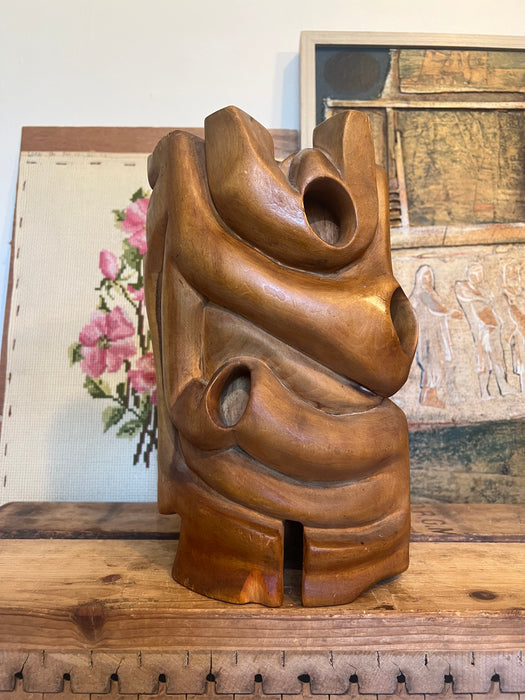 Vintage handmade abstract wood sculpture in mid century modern style with faces depicted.