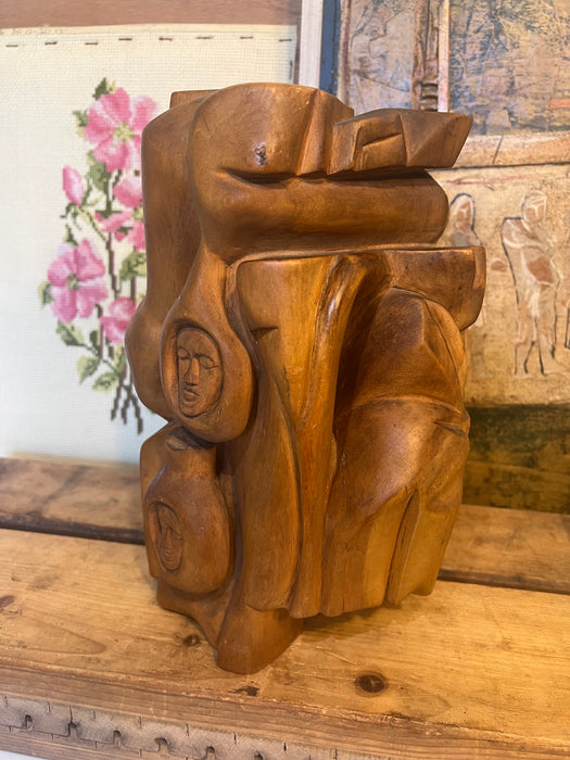 Vintage handmade abstract wood sculpture in mid century modern style with faces depicted.