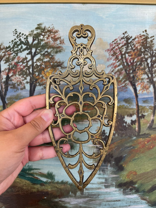 Brass Toned Cast Trivet with Ornate Victorian Design.